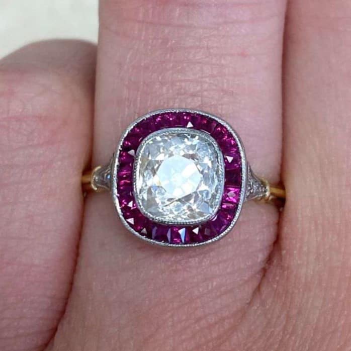 1.68 carat SI1 L color cushion cut diamond set in a platinum bezel with a halo of rubies.